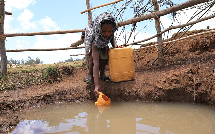 Mädchen holt Wasser aus einer Wasserstelle (Foto)